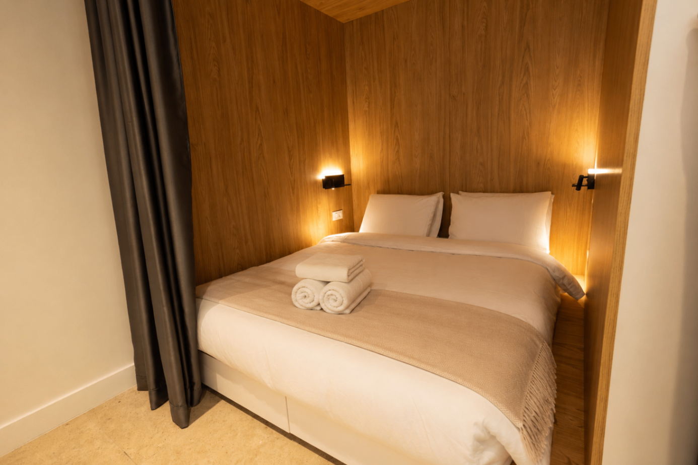 Niriis Suite 1 bedroom with warm wood surround and soft bedside lighting
